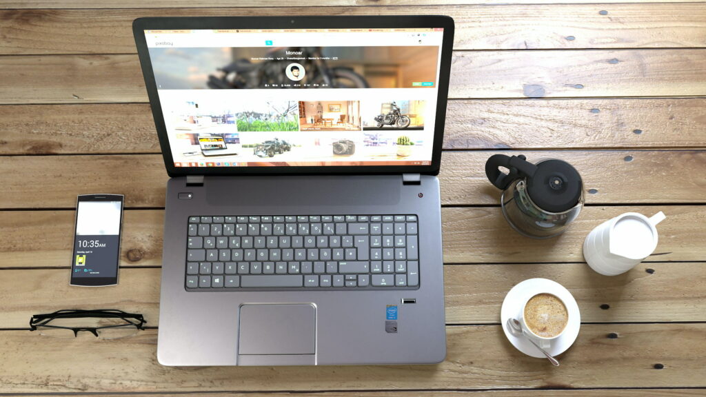 Laptop on desk with coffee, milk and cream